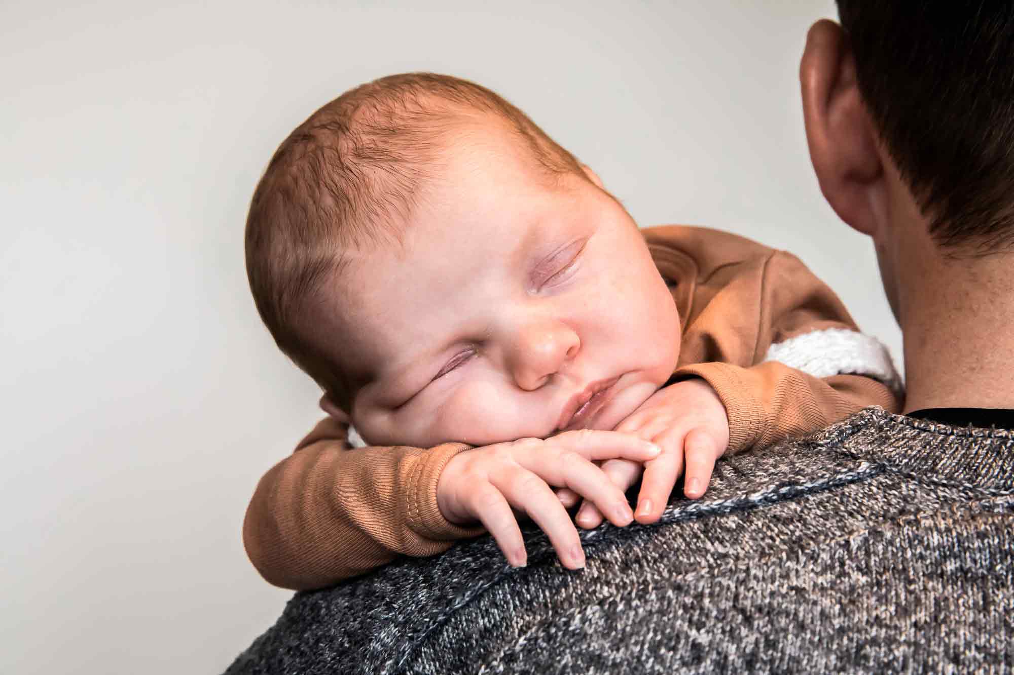 Babyshoot thuis met baby bij de papa lekker slapen