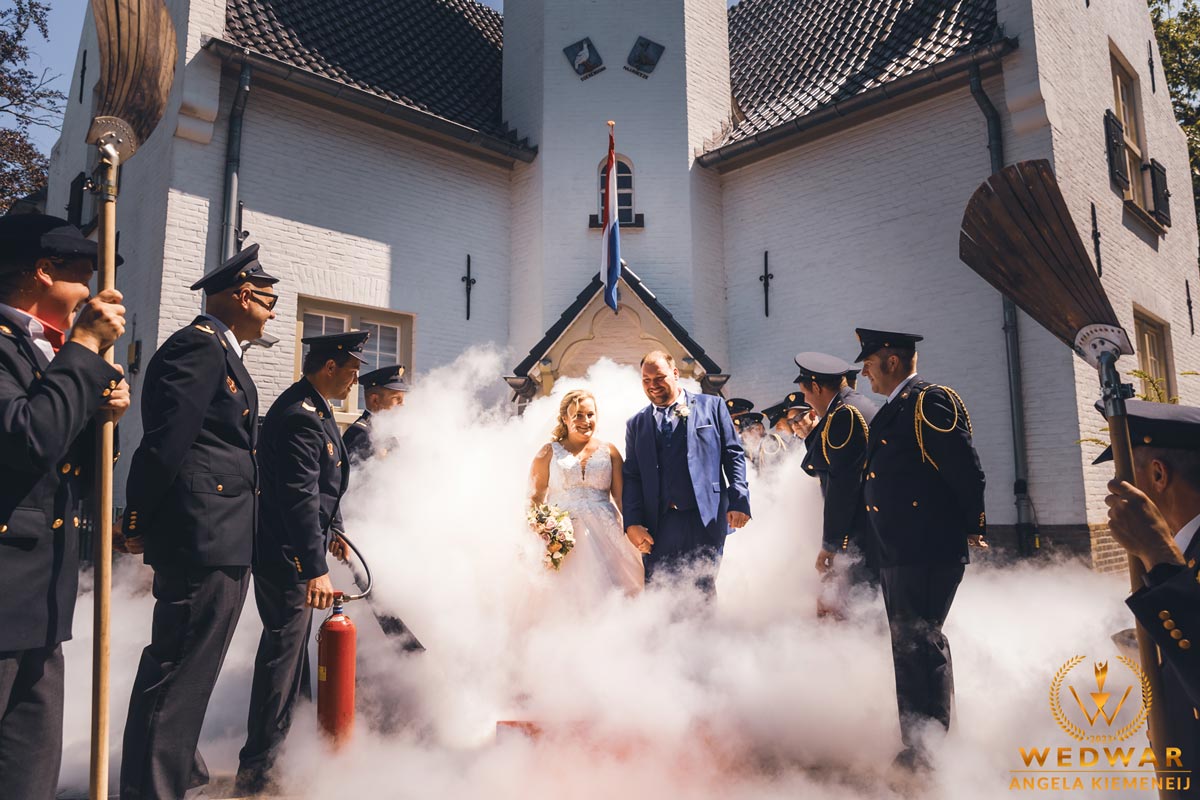 Bruiloftreportage Angela Kiemeneij waarbij het bruidspaar bij het naar buiten lopen wordt opgewacht door de brandweer in Maarheeze