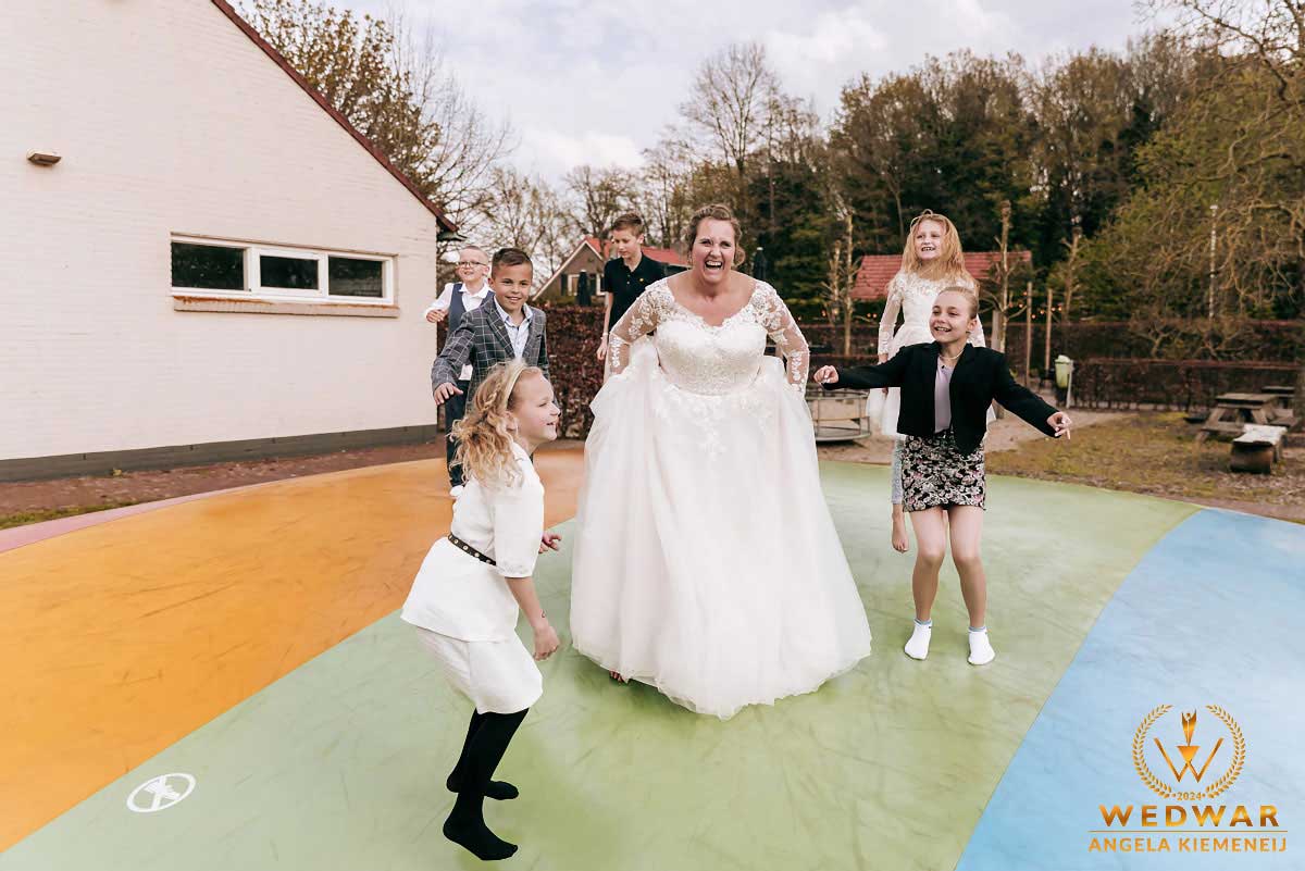 Bruiloftreportage Angela Kiemeneij waar bij de bruid mee gaat spelen met de kinderen in Oirschot gefotografeerd door de trouwfotograaf.