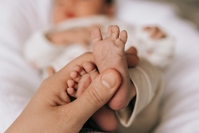 Lieve babyvoetjes worden vastgehouden door de handen van mama