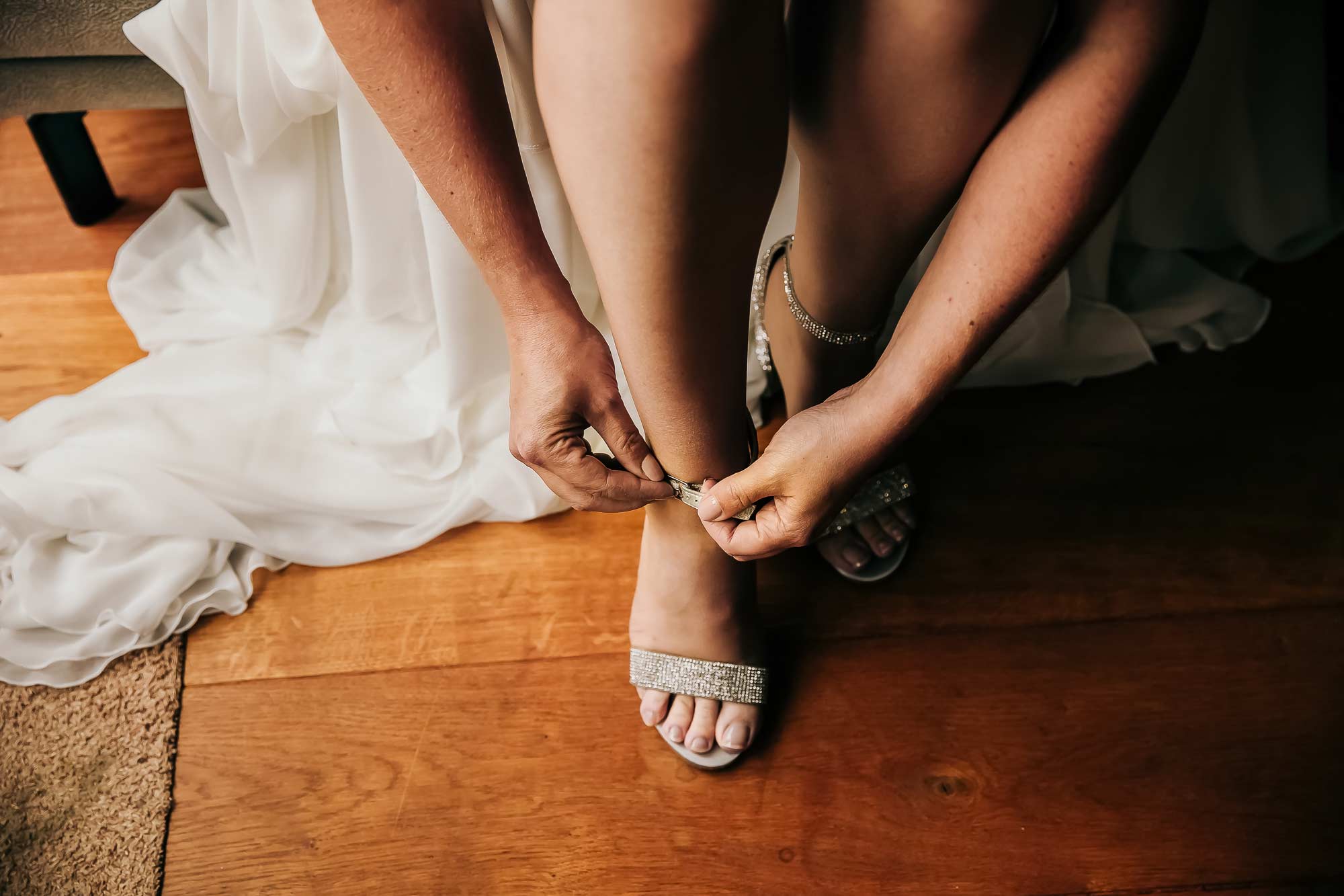 Je ziet hier een bruid die bezig is met haar schoenen aan te doen. Het was makkelijker geweest als ze dat had gedaan voordat ze haar trouwjurk had aangetrokken.