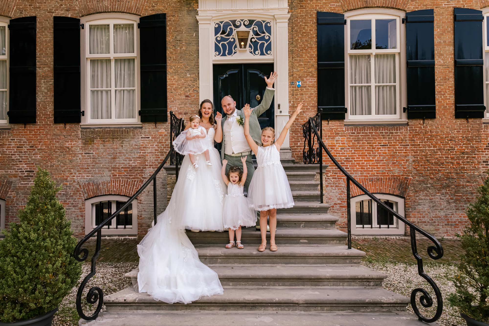 Bruidspaar gaat samen met de bruidsmeisjes op de foto op de bekende trap. Hieperdepiep Hoera!