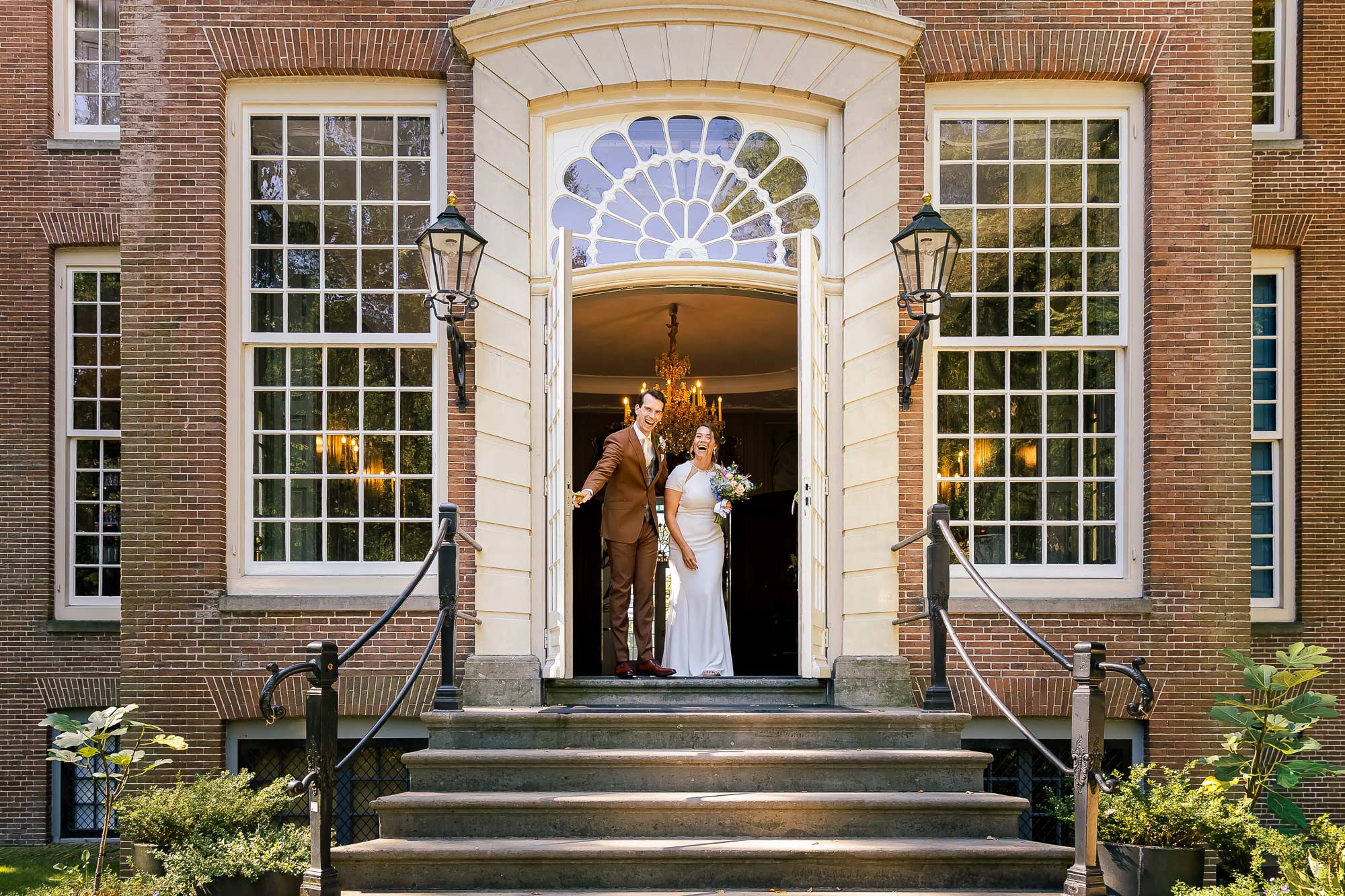 Blij bruidspaar die net na de first-look weer even naar buiten ging.