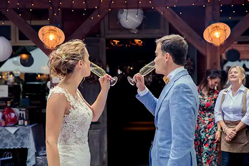 Bruidspaar geniet van een glaasje champagne en kijkt ondertussen naar de trouwlocatie Meneer van Eijck in Oisterwijk.